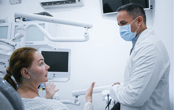 A professional dentist at Cancun Dental Design having a detailed consultation with a female patient in a modern dental office.