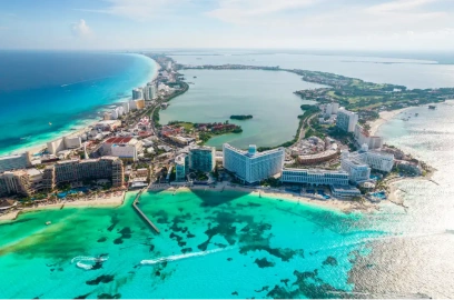 Aerial panoramic view of the Cancun Hotel Zone and Caribbean Sea, the ultimate location for a 'dental vacation' combining veneers or implant treatments with a luxury beach getaway.
